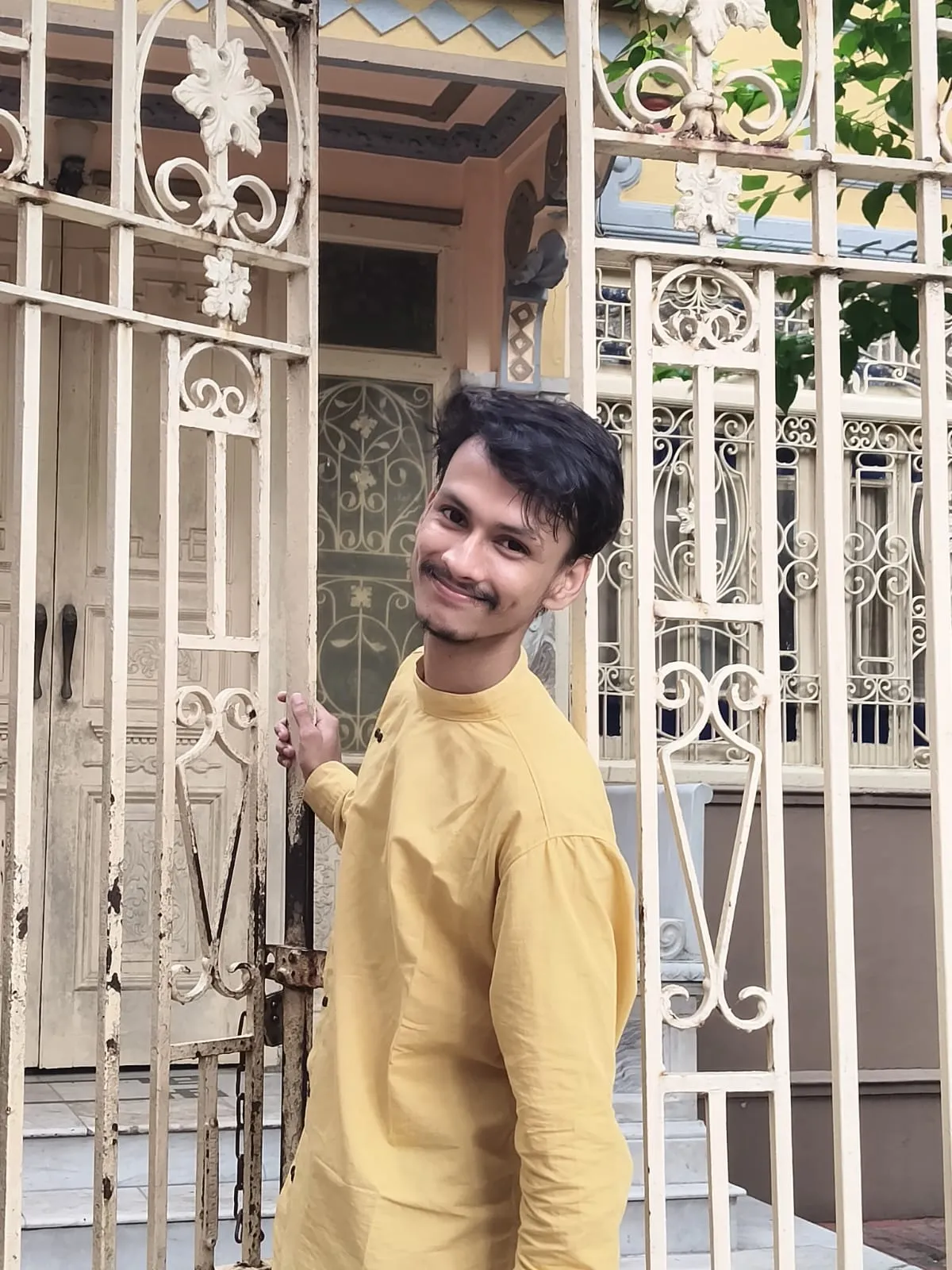 Yogesh in a yellow kurta at an old Kolkata gate, smiling