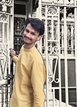 Yogesh smiling in a yellow kurta at an old iron gate